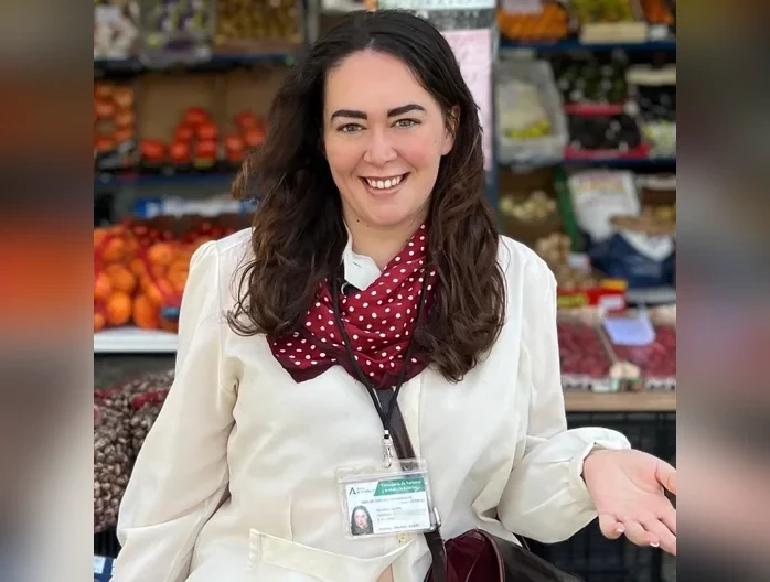 Clara, official tourist guide in Seville, wearing the official guide license badge at a market stall